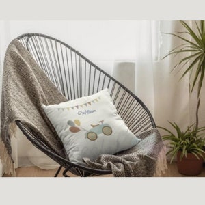 May include: A white pillow with a blue and yellow toy car and balloons on it. The pillow has the name "William" printed on it in purple.
