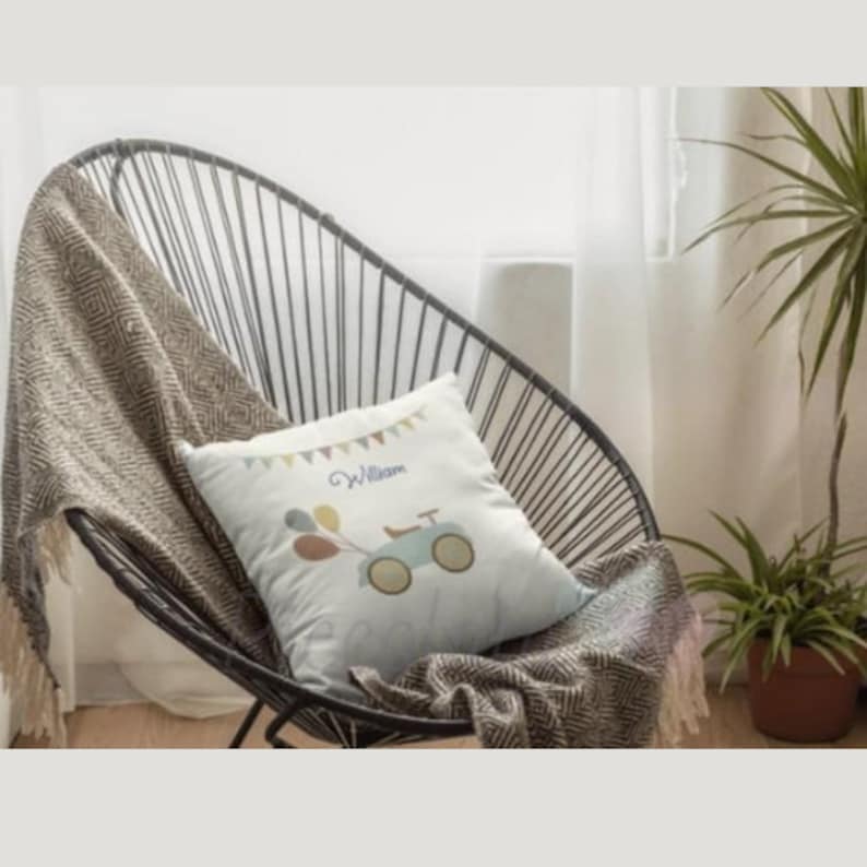 May include: A white pillow with a blue and yellow toy car and balloons on it. The pillow has the name "William" printed on it in purple.