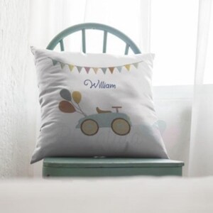 May include: White pillow with a blue toy car, balloons, and a banner with the name "William" embroidered on it.