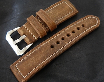 May include: A brown leather watch strap with white stitching and a silver buckle. The strap has multiple holes for adjusting the fit.