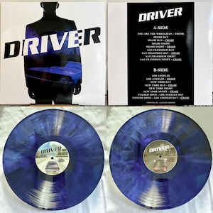 Puede incluir: Un disco de vinilo azul y plateado con la palabra "DRIVER" impresa en la etiqueta. El disco está en una funda de plástico transparente. El disco es una banda sonora de la película "Driver".