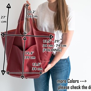 May include: A large, burgundy leather tote bag with a zippered pocket on the front. The bag measures 27 inches tall, 15.4 inches wide, and 13.5 inches deep. The bag can be folded to adjust the width from 34 to 74 cm.