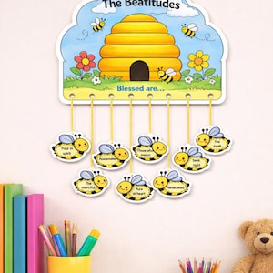 May include: A colorful, illustrated wall hanging featuring a yellow beehive with bees and flowers, labeled "The Beatitudes." Below, eight bee-shaped tags with phrases like "Poor in spirit" and "Peacemakers" hang from the top. The text "Printable Bee-atitudes Craft" is also visible.