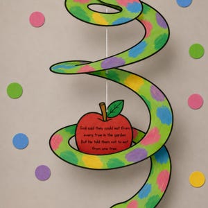 May include: A whimsical, handmade papercraft snake with a green body, colorful polka dots, and a red apple. The apple has text that reads "God said they could eat from every tree in the garden But He told them not to eat from one tree."