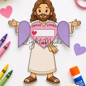 May include: A printable paper craft featuring a cartoon figure of Jesus with brown hair and a beard, wearing a beige robe and brown sandals. The figure holds a large pink heart with the text Jesus Loves and a blank space for writing.