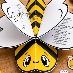 May include: A 3D paper bee craft featuring yellow and black stripes, white wings with printed text including The Beatitudes Matthew 5:3-10, and a smiling face. The top banner reads Printable Bee-attitudes Craft and a label says Digital Download.