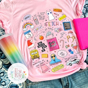 Może przedstawiać: Różowa koszulka z różnymi ilustracjami z motywem Mean Girls, w tym tekst "Fetch", "You can't sit with us", "On Wednesdays we wear pink" i "She doesn't even go here".