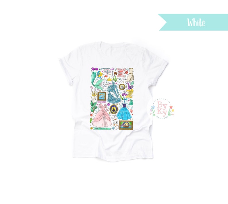 Pu&ograve; includere: Maglietta bianca con una stampa grafica colorata di vari personaggi e oggetti di principesse e sirene Disney. La grafica include Ariel, Cenerentola e Ursula. Il testo sulla grafica include "Part of Your World", "Happily Ever After" e "The Sea, The Sea".