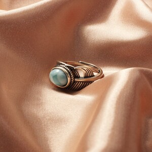 May include: A gold ring with a blue oval gemstone set in a feather design.