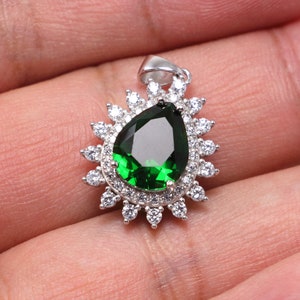 Close-up of oval green spinel pendant with halo of cubic zirconia, set in polished silver