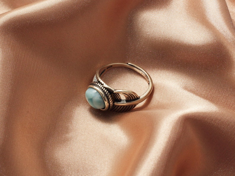 May include: A silver ring with a blue gemstone and a feather design.