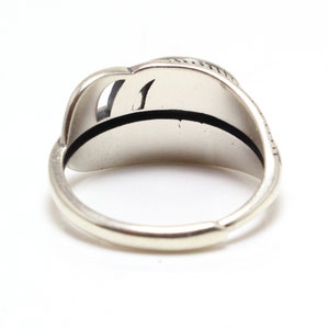 May include: A silver ring with a textured design on the band. The ring is open on the side and has a smooth, rounded interior.