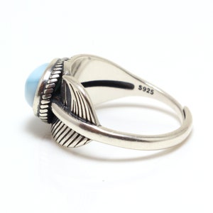 May include: A silver ring with a light blue stone and a feather design. The ring is marked with "S925" on the inside.