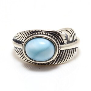 May include: A silver ring with a blue gemstone set in a feather design.