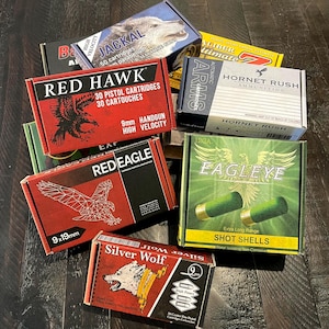 May include: A collection of ammunition boxes with various brand names and graphics. Boxes include "Red Hawk", "Red Eagle", "Eagle Eye", "Silver Wolf", and "Jackal". The boxes feature images of eagles, wolves, and other wildlife.