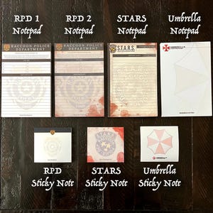 May include: A collection of seven paper stationery items including four rectangular notepads and three square sticky notes. The designs feature Raccoon Police Department, S.T.A.R.S., and Umbrella Corporation branding with various blood splatter and logo motifs.