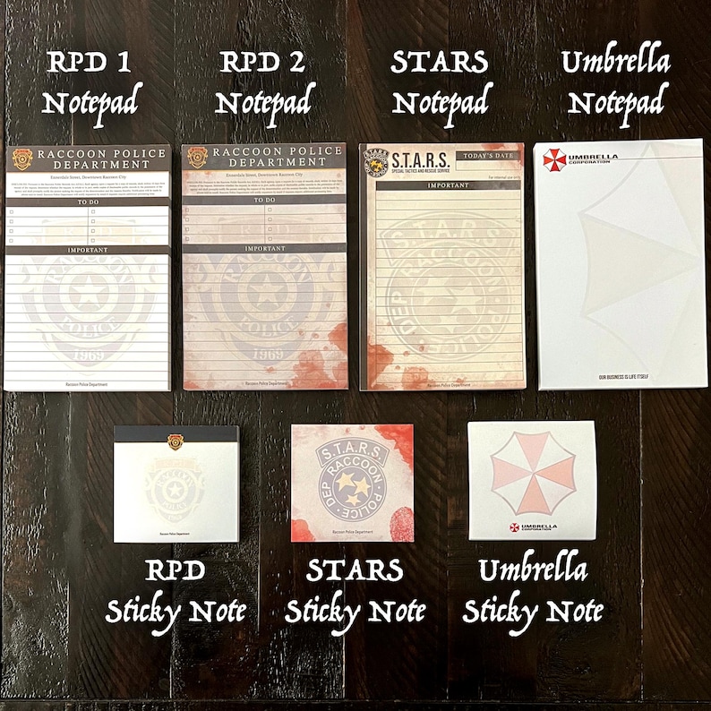 May include: A collection of seven paper stationery items including four rectangular notepads and three square sticky notes. The designs feature Raccoon Police Department, S.T.A.R.S., and Umbrella Corporation branding with various blood splatter and logo motifs.