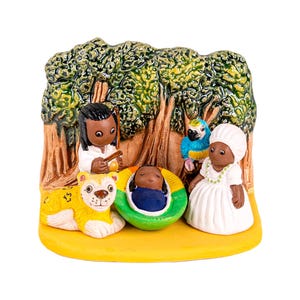 May include: A colorful ceramic figurine depicting a nativity scene. The scene includes figures of people, a lion, a parrot, and a baby in a manger. The background features a tree and a yellow base.