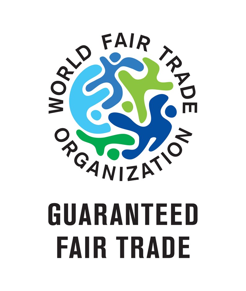 Puede incluir: Un logotipo circular con el texto "WORLD FAIR TRADE ORGANIZATION" en letras negras alrededor de una imagen estilizada de tres personas que se dan la mano en azul, verde y azul claro. El texto "GUARANTEED FAIR TRADE" est&aacute; debajo del logotipo.