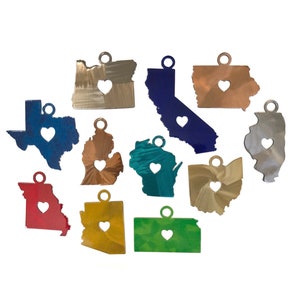 May include: A set of 12 metal state charms with a heart cutout in the center. The charms are in various colors, including gold, silver, blue, red, green, and copper. Each charm features a different state outline.