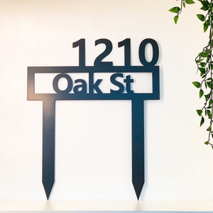 May include: Black metal yard sign with the address "1210 Oak St" in white lettering.