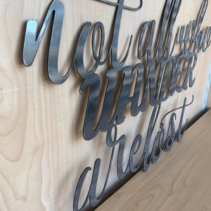 May include: Metal wall art with the text "Not all who wander are lost".