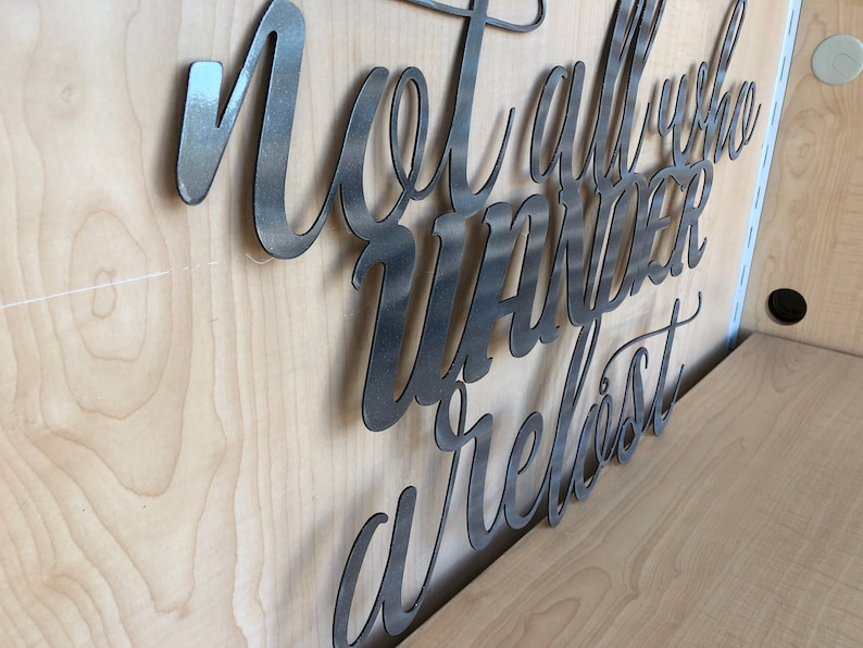 May include: Metal wall art with the text "Not all who wander are lost".