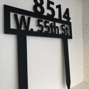May include: Black metal house number sign with the numbers 8514 and the text "W. 55th St" on a white background.