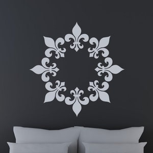 May include: A gray bed with white bedding and two white nightstands with gold lamps. A gray and white decorative stencil is on the wall behind the bed.