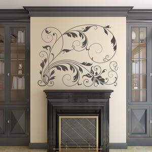 Peut inclure: Décoration murale florale tourbillonnante grise au-dessus d'une cheminée noire avec un écran doré. La pièce comprend des meubles gris avec des portes vitrées. Le motif floral crée une ambiance élégante.