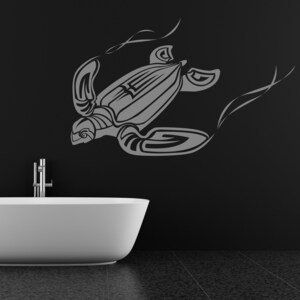 Op de afbeelding: Een grijze muursticker van een schildpad boven een witte badkuip. Het schildpadontwerp is gestileerd met gebogen lijnen en vormen. De badkamer heeft een zwarte muur en een donkergrijze tegelvloer.