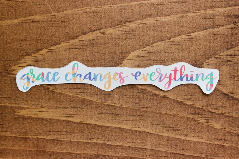 May include: A white sticker with a colorful, wavy, handwritten font that reads "grace changes everything".