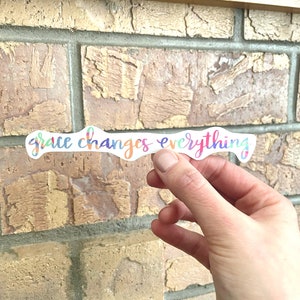May include: A colorful sticker with the text "grace changes everything" in a rainbow gradient.