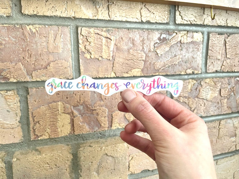 May include: A colorful sticker with the text "grace changes everything" in a rainbow gradient.