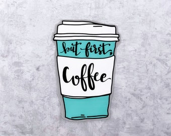 Puede incluir: Una taza de café azul turquesa y blanca con el texto "but first, coffee" en letras cursivas negras.
