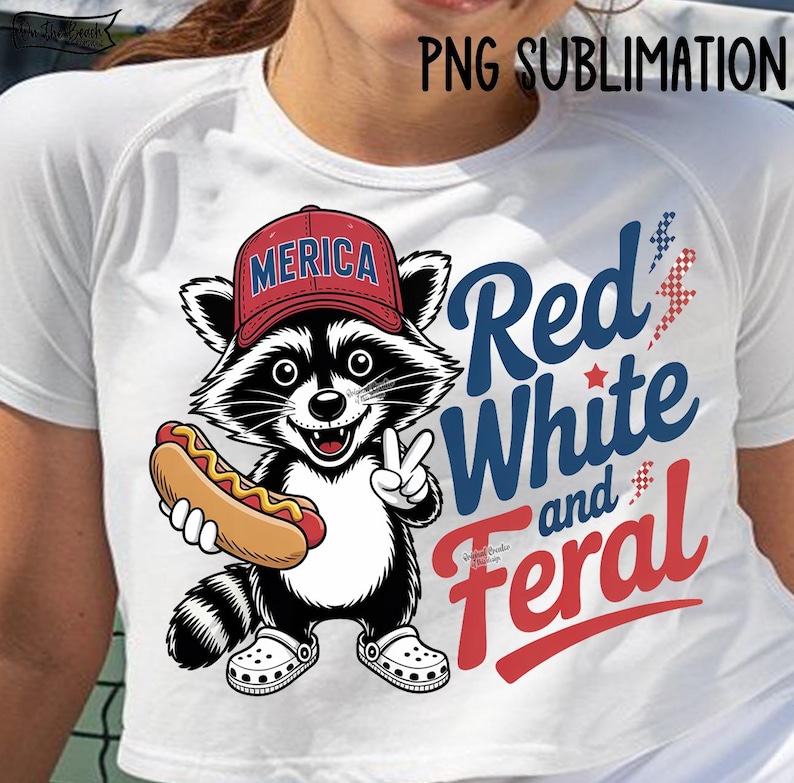May include: White t-shirt featuring a cartoon raccoon wearing a red hat with "MERICA" on it, holding a hot dog, and giving a peace sign. The shirt has the text "Red, White, and Feral" in red and blue.