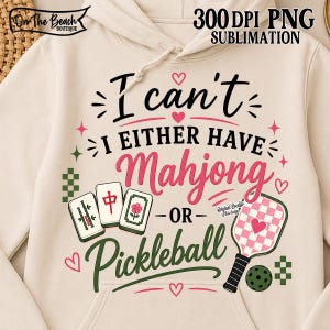 May include: A cream-colored hoodie featuring a graphic design with the text I can't I EITHER HAVE Mahjong OR Pickleball. The design includes three mahjong tiles, a checkered pickleball paddle with a heart, a pickleball, and small pink hearts.