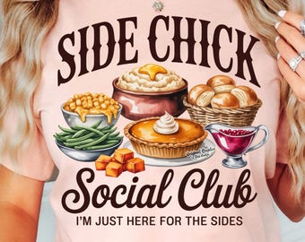 May include: A pale pink t-shirt with a graphic design. The design features the words "SIDE CHICK Social Club" and the phrase "I'M JUST HERE FOR THE SIDES." The design includes illustrations of various side dishes like mashed potatoes, pie, and rolls.