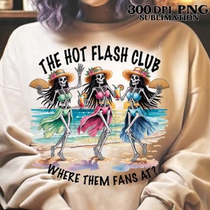 May include: A beige sweatshirt featuring a colorful graphic of three skeleton figures on a beach. The skeletons wear straw hats, skirts, and hold drinks and fans. Text reads "THE HOT FLASH CLUB" and "WHERE THEM FANS AT?"