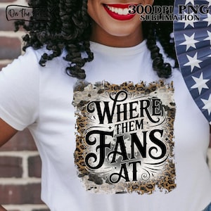 以下が含まれることがあります： ヒョウ柄と使い古された背景に、装飾的な黒いフォントで「Where Them Fans At」というテキストがプリントされた白いTシャツ。 このシャツは昇華プリントです。