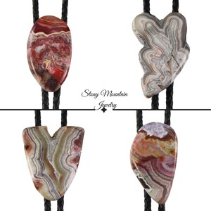 May include: Four bolo ties with different agate stone designs. The stones are all different colors and patterns, including red, white, and brown. The bolo ties are made with black leather cords. The text "Stony Mountain Jewelry" is visible in the center of the image.