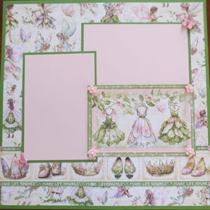 May include: A scrapbook page with a fairy theme. It features pink and green accents, with spaces for photos. The design includes images of fairies, dresses, shoes, and crowns. The text "MAKE LIFE SPARKLE" is repeated along the bottom.