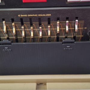 May include: Close-up of a black stereo system with a 10-band graphic equalizer, volume knobs, and a karaoke button. The equalizer has sliders that can be adjusted to change the sound.