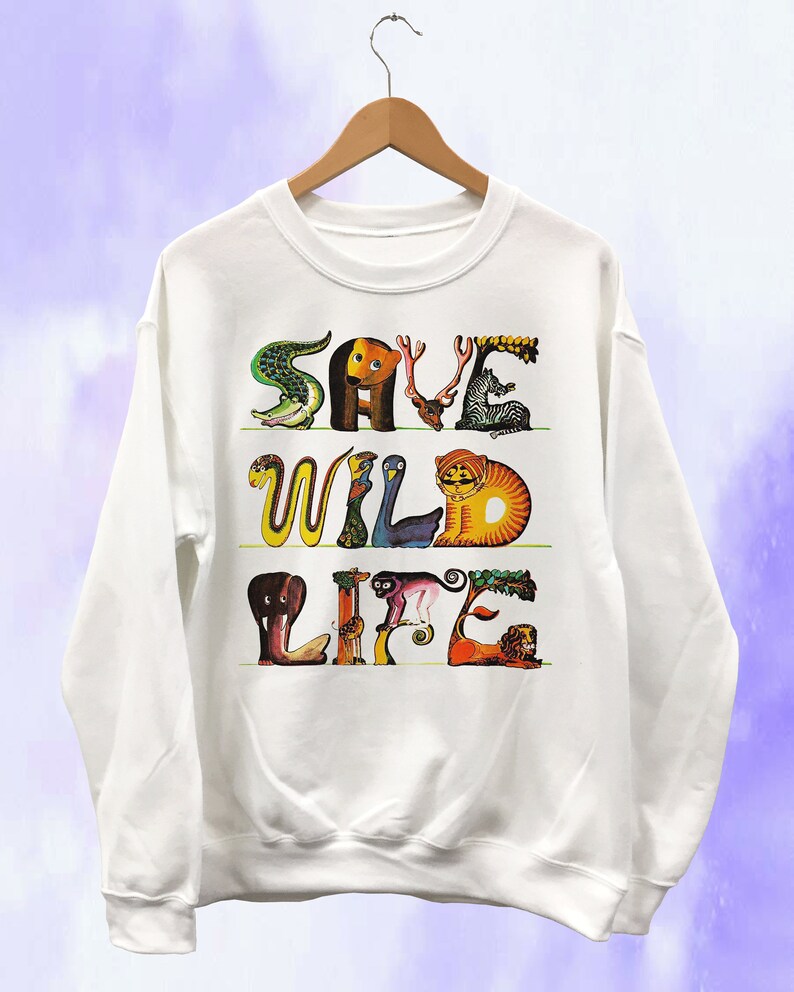 May include: White sweatshirt with the words "SAVE WILD LIFE" in colorful animal-shaped letters. The design includes a crocodile, bear, zebra, snake, bird, tiger, elephant, monkey, and lion. The sweatshirt is hanging on a wooden hanger.
