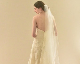 May include: A white wedding dress with a lace bodice and a flowing skirt. The dress is paired with a white veil.