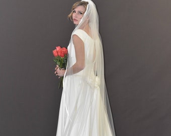 Könnte beinhalten: Ein weißes Brautkleid mit einem langen Schleier und einem Strauß roter Rosen.