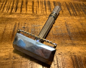 May include: A silver and gold safety razor with a textured handle. The razor has a chrome finish and a gold trim.