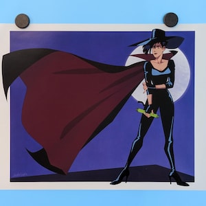 May include: A woman in a black outfit and a wide-brimmed hat stands with a cape flowing behind her. She holds a green object in her hand. The background is a dark blue with a white moon.