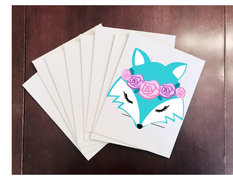 May include: A stack of white cardstock paper with a turquoise fox face with closed eyes and a pink and purple flower crown on the top sheet.