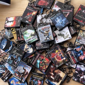 Puede incluir: Una colección de llaveros de juegos de PlayStation 2 con varios títulos populares, incluyendo Resident Evil, Silent Hill y Clock Tower. Los llaveros están hechos de plástico negro y presentan la portada del juego.
